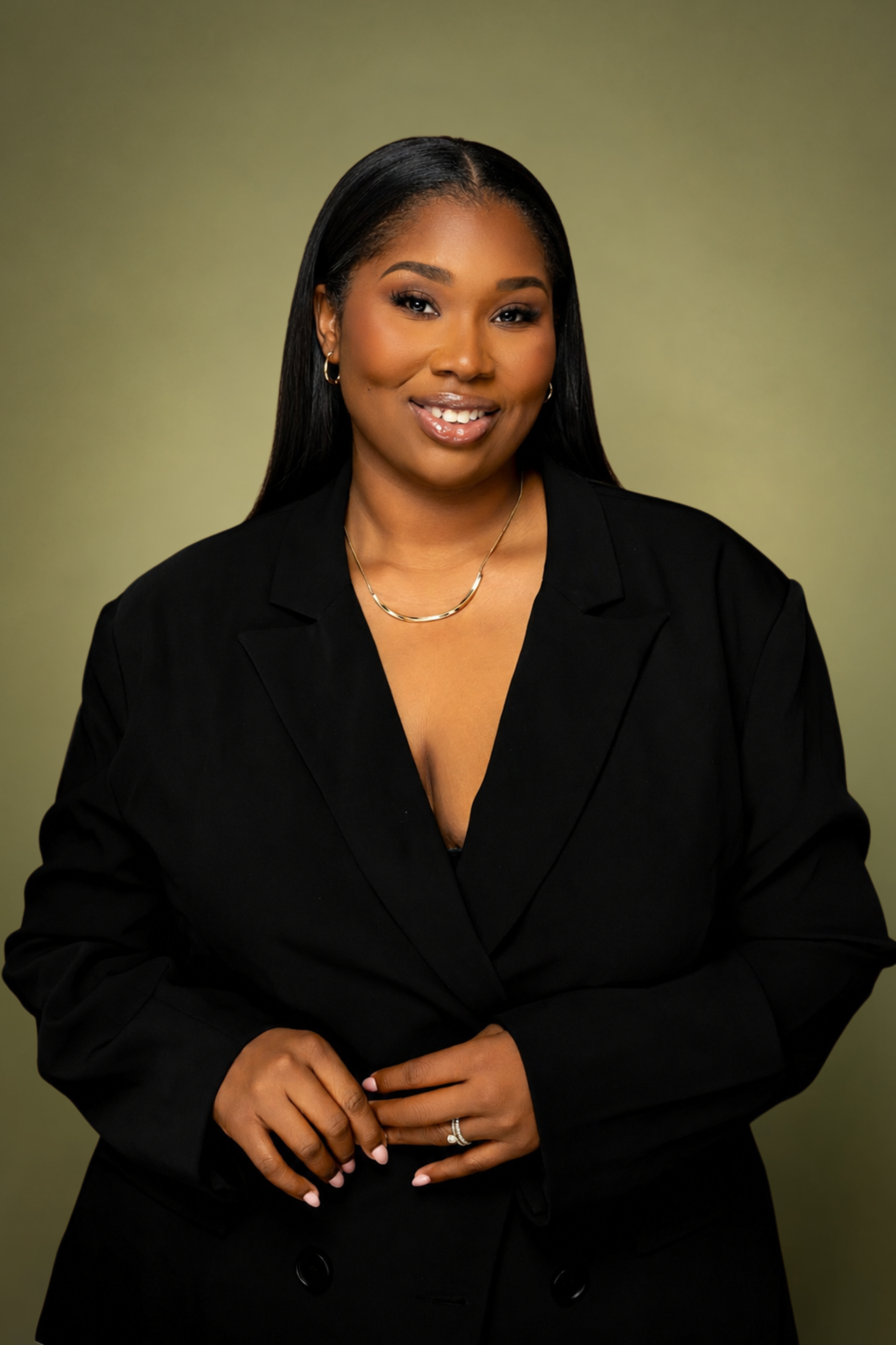 Jasmine Howell in a black suit against an olive green background